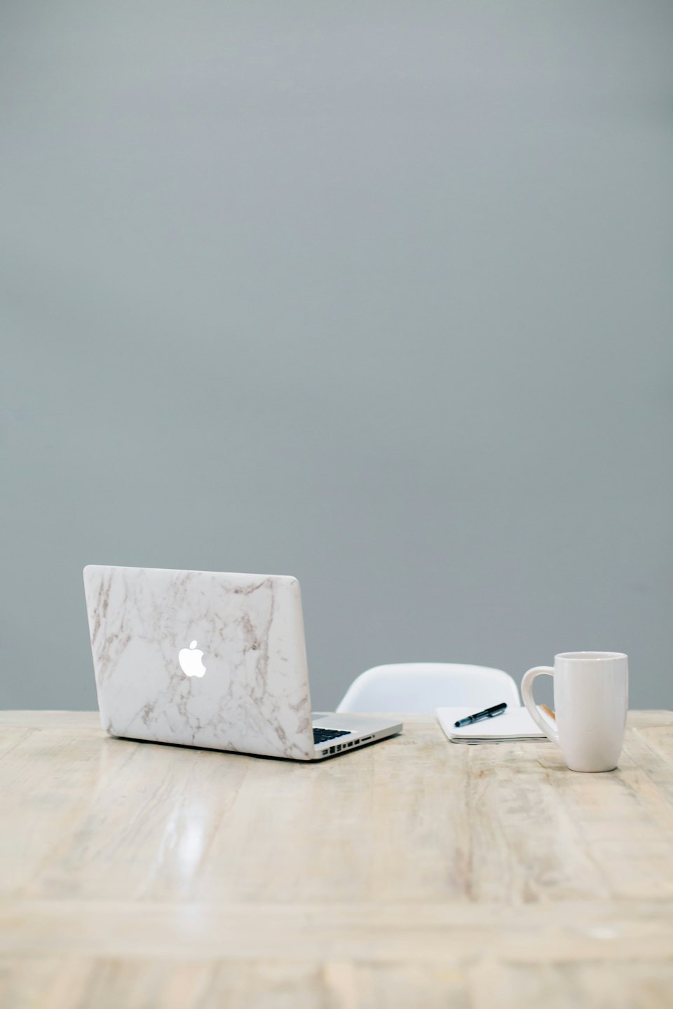 Laptop, taccuino e tazza di caffè su una scrivania di legno.